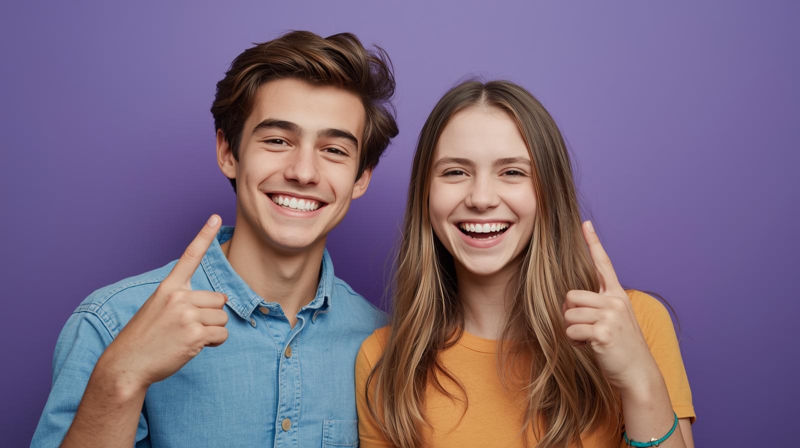 Uśmiechnięta para nastolatków wskazuje palcem do góry na fioletowym tle.
